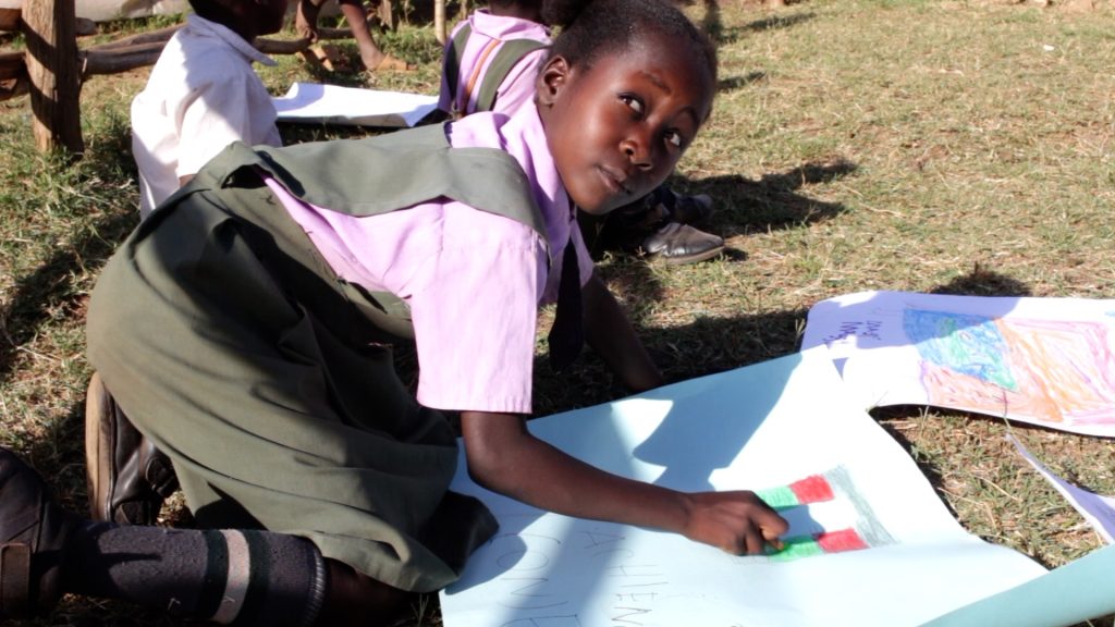 Girl at orphanage in Kenya where many children are living with HIV AIDS. Girl is attending a storytelling event and painting he impression of the story told.