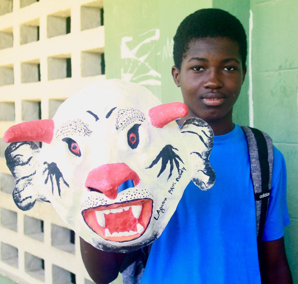 A kid showing the mask he created during mask making workshop