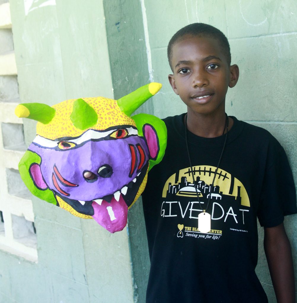 a boy holding a mask she created during CPI workshop
