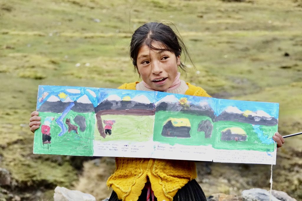 A Quechua girl from Peru proudly shows her first watercolor painting, created during Childsplay International’s global storytelling and arts program.